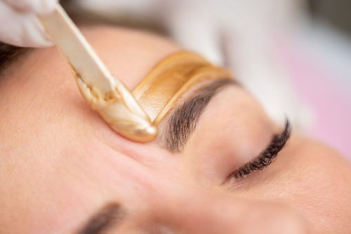 Sugar hair removal from woman body. Wax epilation spa procedure. Procedure beautician female. Eyebrow